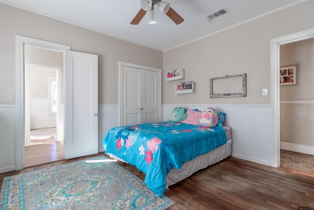 bedroom featuring a wainscoted wall, a closet, dark wood finished floors, and visible vents