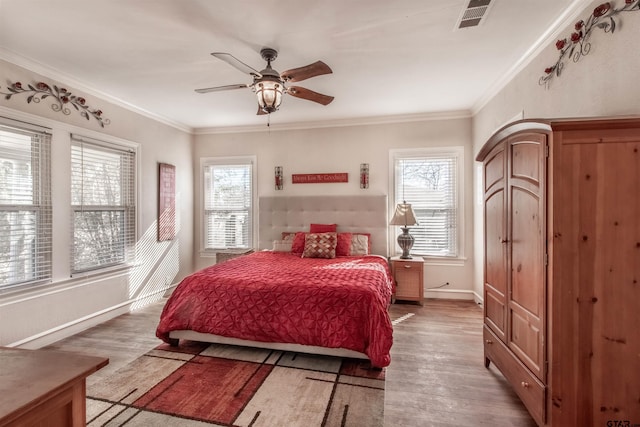 bedroom featuring visible vents, crown molding, baseboards, and wood finished floors