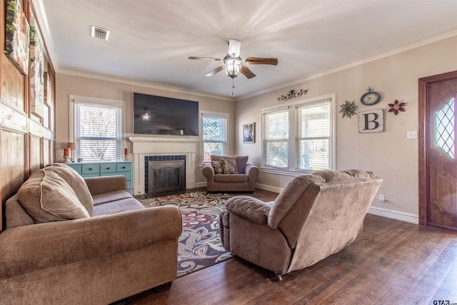 living area featuring ceiling fan, visible vents, baseboards, dark wood-style floors, and crown molding