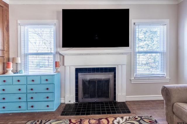 living room featuring dark wood-style floors, a fireplace, baseboards, and crown molding