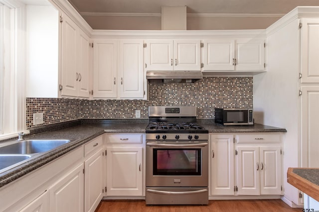 kitchen featuring white cabinets, under cabinet range hood, dark countertops, and stainless steel appliances