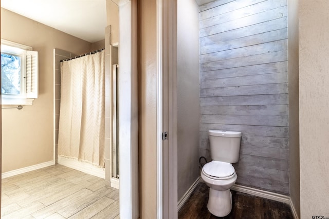 bathroom with a shower with curtain, baseboards, toilet, and wood finished floors