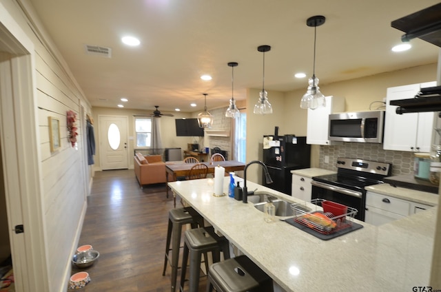 kitchen featuring white cabinetry, decorative light fixtures, dark hardwood / wood-style floors, and appliances with stainless steel finishes