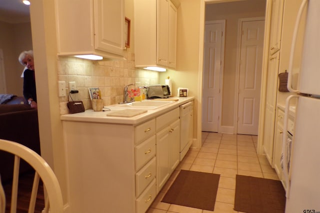 kitchen featuring white appliances, white cabinets, light tile patterned floors, and sink