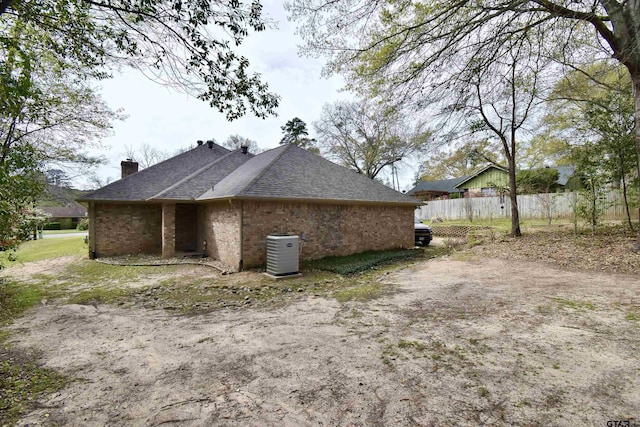 1406 Kingspark Dr, Tyler, TX 75703 - view of side of home with brick siding, a chimney, central air condition unit, and a shingled roof
