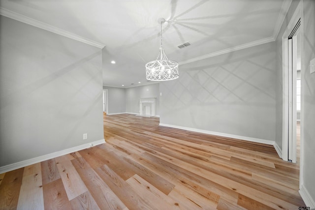 unfurnished dining area featuring light wood-type flooring, crown molding, and a notable chandelier