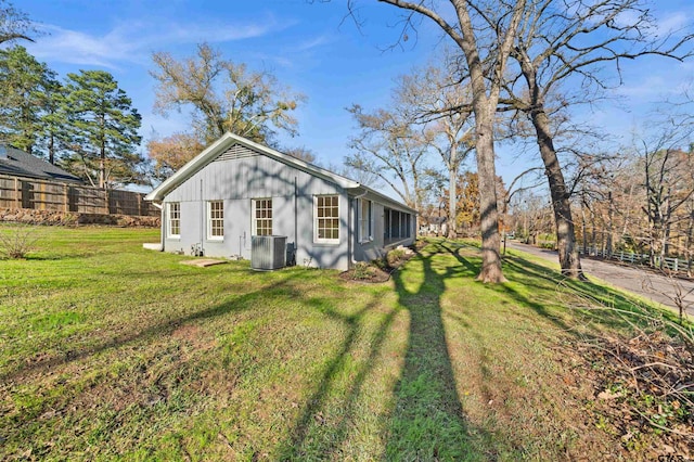 view of side of property featuring central air condition unit and a lawn