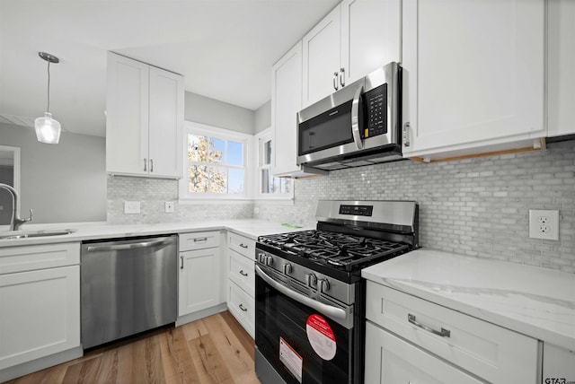 kitchen with backsplash, white cabinets, sink, light hardwood / wood-style flooring, and appliances with stainless steel finishes