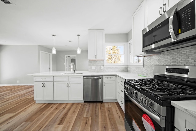 kitchen with white cabinetry, pendant lighting, light wood-type flooring, and appliances with stainless steel finishes