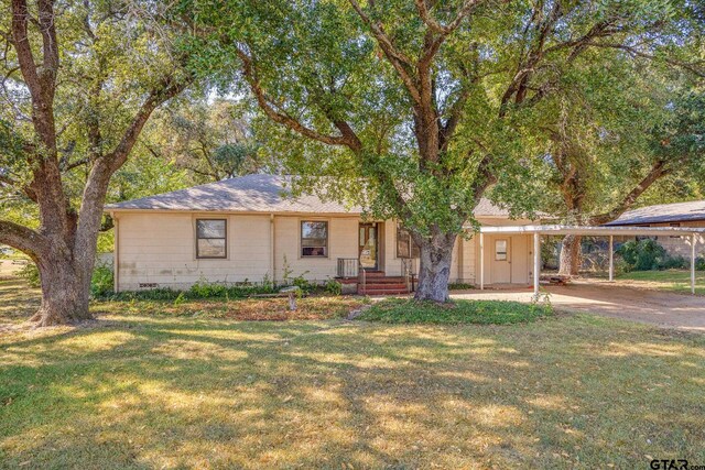 ranch-style home featuring a front lawn and a carport