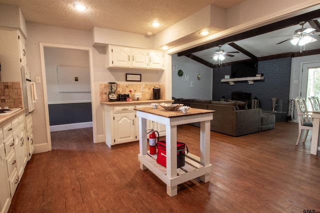 kitchen featuring a textured ceiling, hardwood / wood-style floors, decorative backsplash, and white cabinets