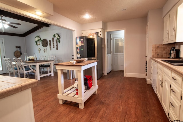 kitchen featuring tile countertops, stainless steel refrigerator, dark hardwood / wood-style flooring, decorative backsplash, and a textured ceiling