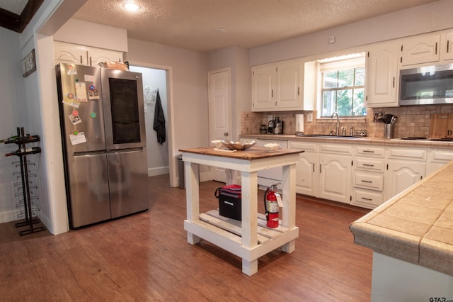 kitchen with sink, white cabinets, backsplash, stainless steel appliances, and a textured ceiling