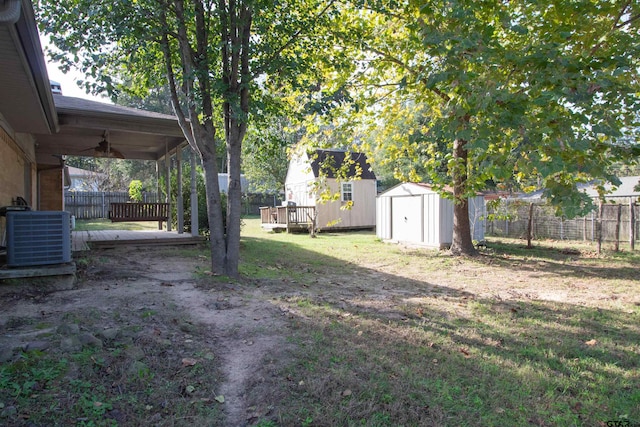 view of yard with a storage shed, a wooden deck, central air condition unit, and ceiling fan