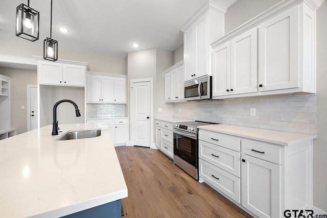 kitchen with pendant lighting, stainless steel appliances, decorative backsplash, white cabinets, and sink