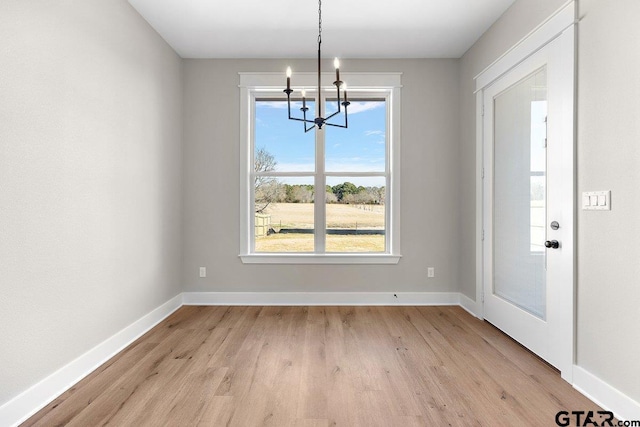 unfurnished dining area featuring light wood-type flooring and an inviting chandelier