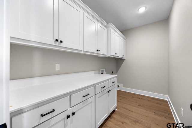 washroom with electric dryer hookup, hookup for a washing machine, cabinets, and light wood-type flooring