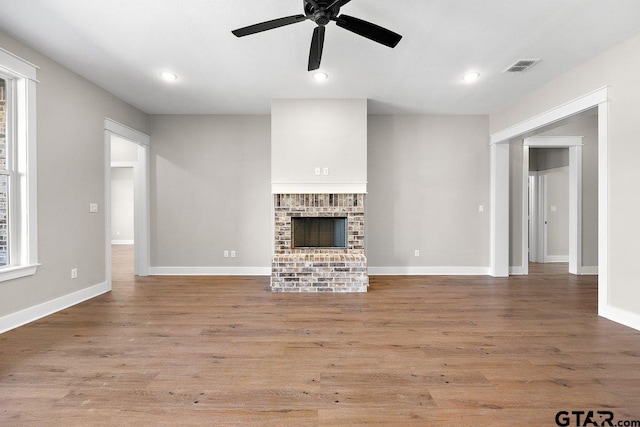 unfurnished living room featuring ceiling fan, light wood-type flooring, and a fireplace