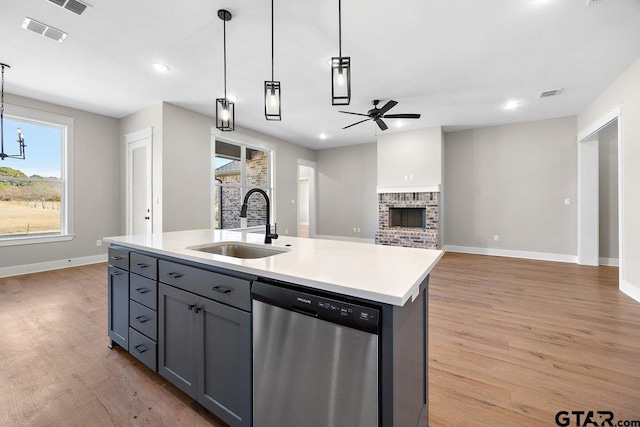 kitchen featuring stainless steel dishwasher, hanging light fixtures, a center island with sink, ceiling fan, and sink