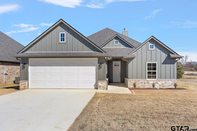 view of front of home with central AC, a front yard, and a garage