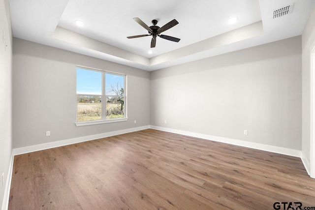 unfurnished room featuring hardwood / wood-style flooring, a raised ceiling, and ceiling fan