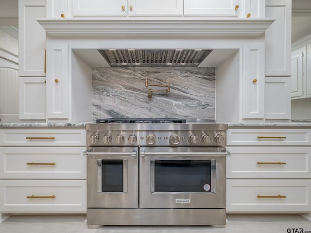 kitchen with double oven range, light stone countertops, white cabinets, and decorative backsplash