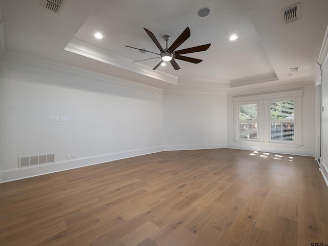 spare room with hardwood / wood-style floors, a tray ceiling, ornamental molding, and ceiling fan