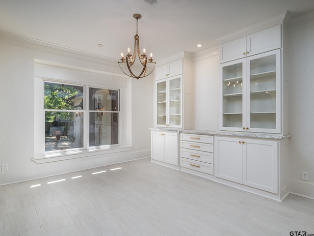 unfurnished dining area with an inviting chandelier and crown molding