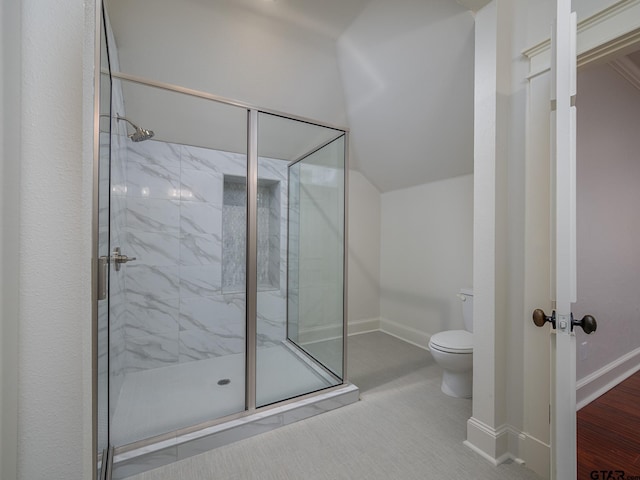 bathroom featuring toilet, a shower with shower door, and vaulted ceiling