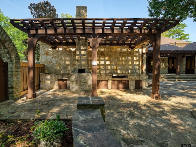 view of patio / terrace featuring exterior kitchen, a fireplace, and a pergola