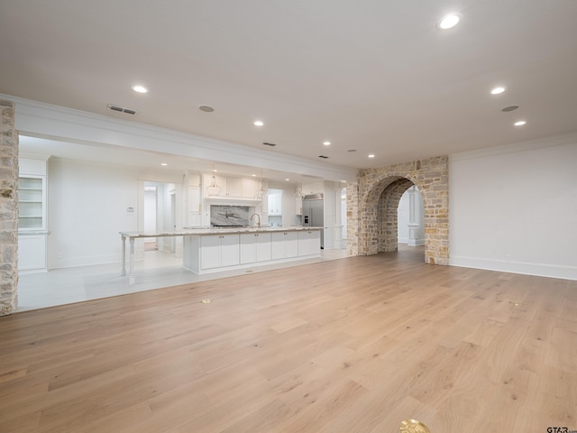 unfurnished living room with ornamental molding, sink, and light hardwood / wood-style flooring