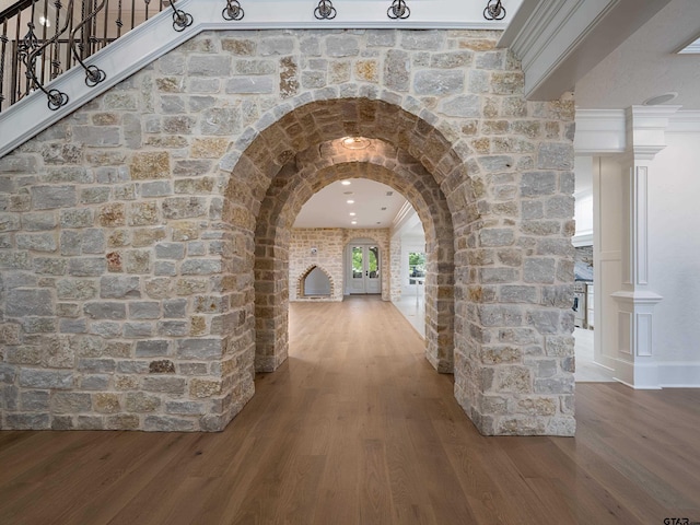 hallway with dark wood-type flooring, ornamental molding, and ornate columns