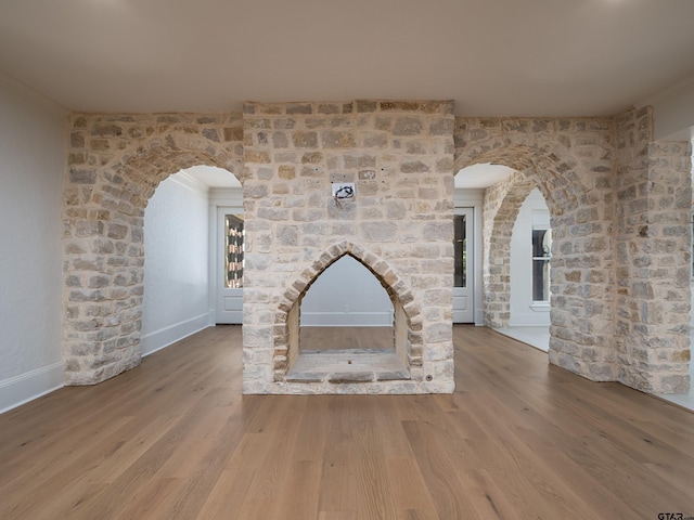 unfurnished living room with a brick fireplace, hardwood / wood-style flooring, and ornamental molding