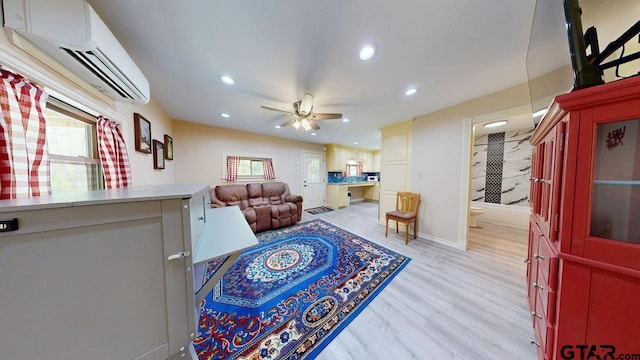 living area with a wealth of natural light, ceiling fan, an AC wall unit, and light wood-type flooring