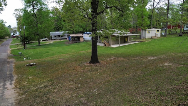 view of yard featuring a storage unit, an attached carport, and an outdoor structure