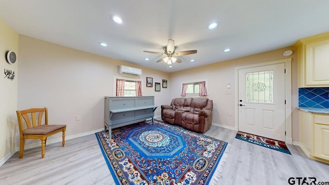 living area with light wood-style flooring, an AC wall unit, recessed lighting, and a ceiling fan
