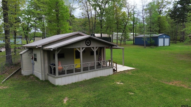 exterior space featuring an outbuilding, a front lawn, metal roof, a storage unit, and a porch