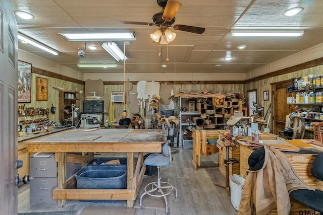 misc room with ceiling fan, a workshop area, a wall unit AC, wooden walls, and hardwood / wood-style flooring