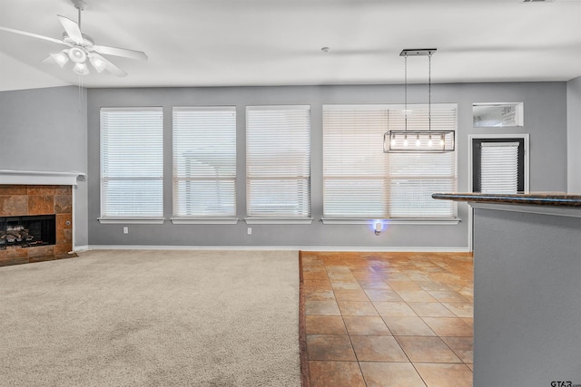 unfurnished living room with light colored carpet, ceiling fan, and a tile fireplace