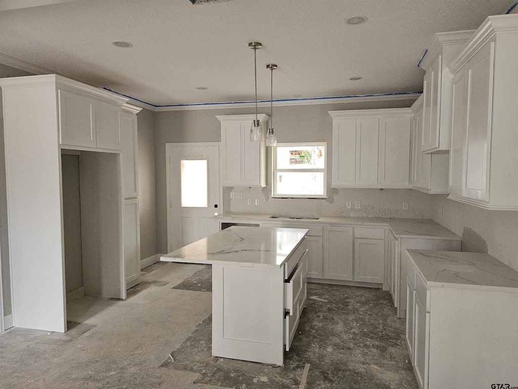 kitchen featuring ornamental molding, white cabinets, a kitchen island, and light stone countertops