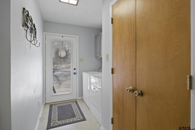 laundry area featuring a textured ceiling, cabinet space, baseboards, and washer and clothes dryer