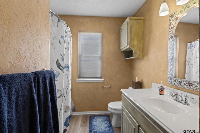 full bath featuring baseboards, toilet, vanity, wood finished floors, and a textured ceiling