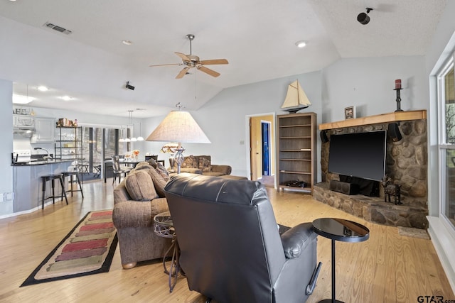 living room featuring visible vents, light wood-style flooring, a ceiling fan, and vaulted ceiling