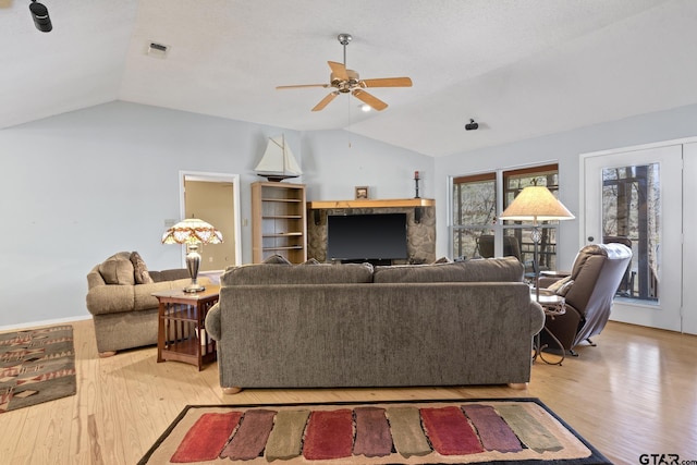 living room featuring visible vents, a ceiling fan, light wood-style floors, and lofted ceiling