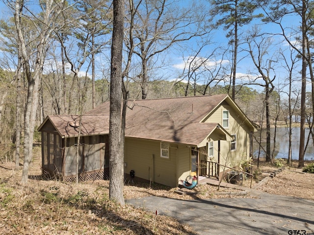 view of front facade featuring a wooded view and a shingled roof