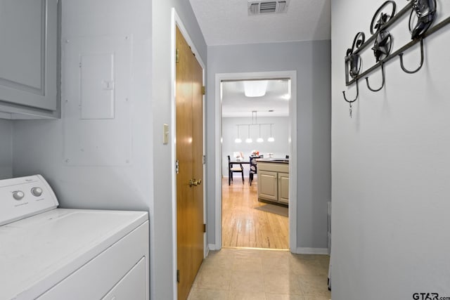 clothes washing area with visible vents, electric panel, washer / clothes dryer, a textured ceiling, and cabinet space