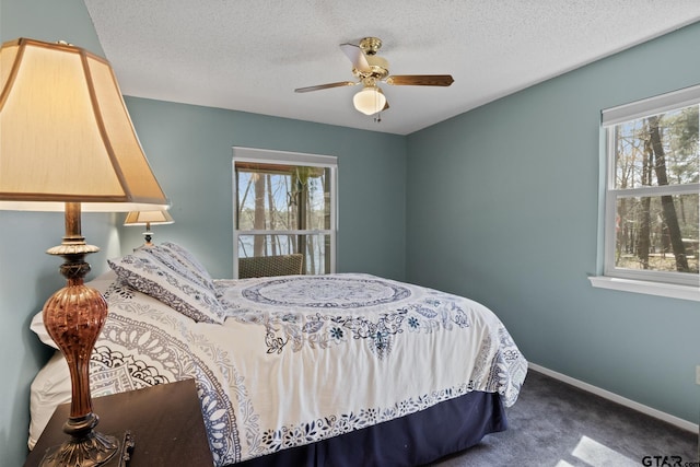 bedroom with baseboards, multiple windows, a textured ceiling, and carpet flooring