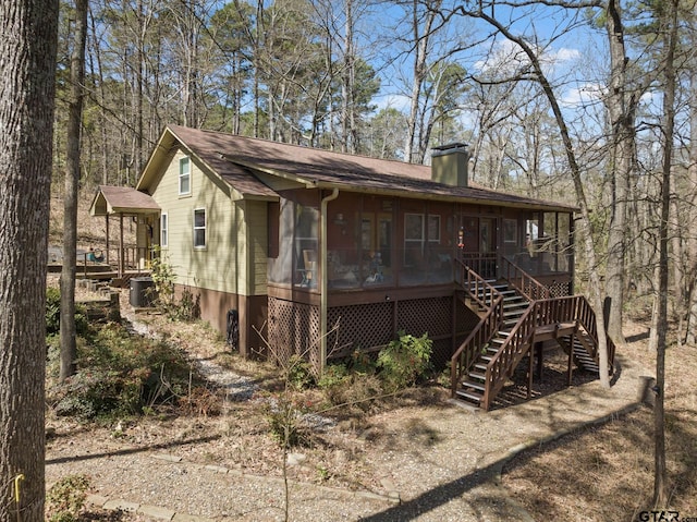 rear view of property featuring stairway, roof with shingles, central AC, a sunroom, and a chimney