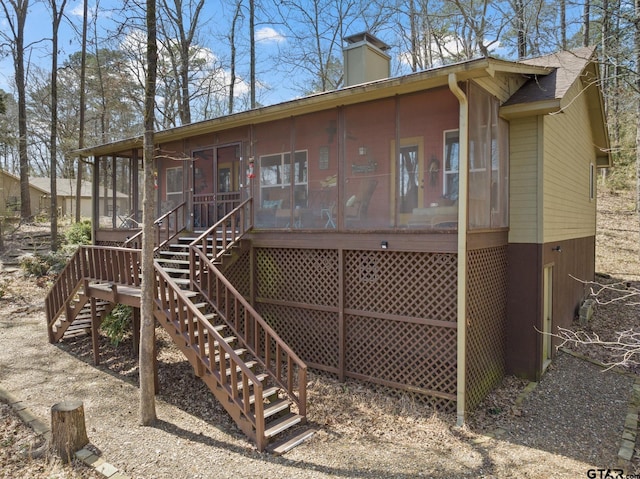 rear view of house with stairs, a sunroom, and a chimney