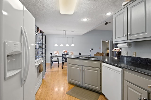 kitchen with white appliances, a peninsula, gray cabinetry, and a sink